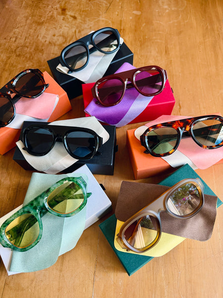 Collection of sunglasses on colorful boxes on a wooden surface